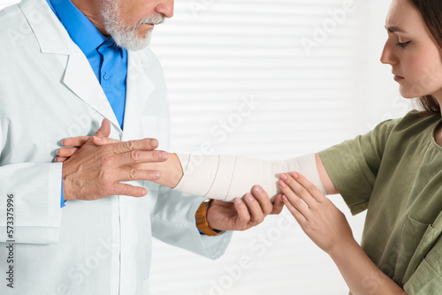 Fototapeta Naklejka Na Ścianę i Meble -  Orthopedist applying bandage onto patient's elbow in clinic, closeup