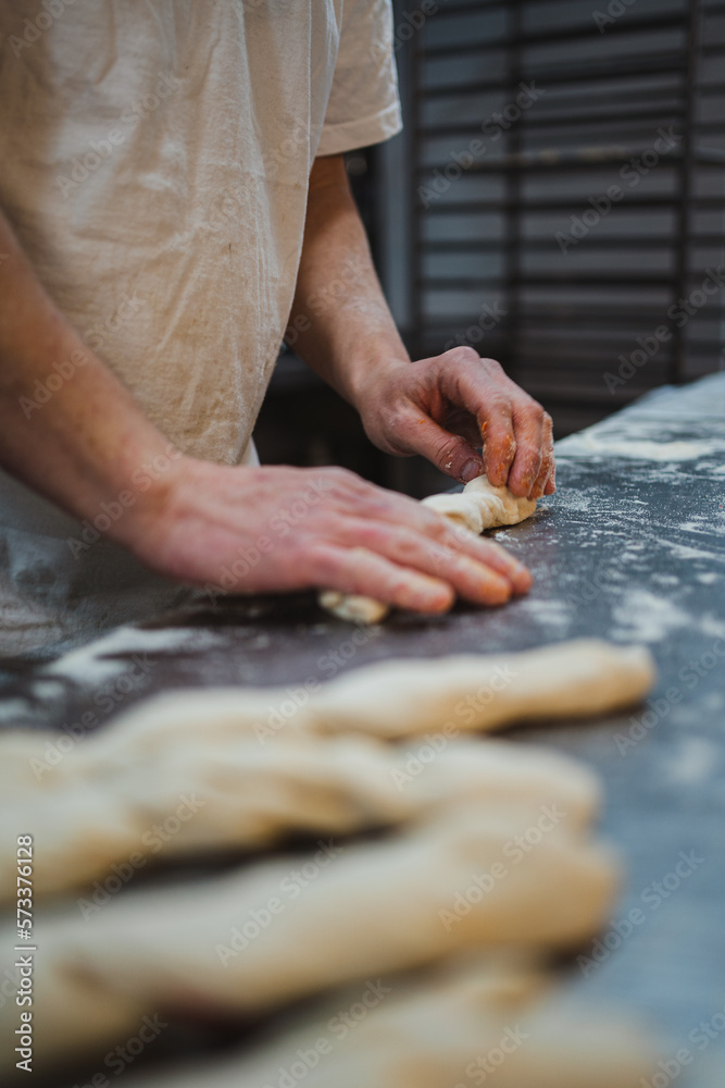 Baker rolling up stuffed bread sticks in a artisan bakery Baker rolling up stuffed bread sticks in a artisan bakery