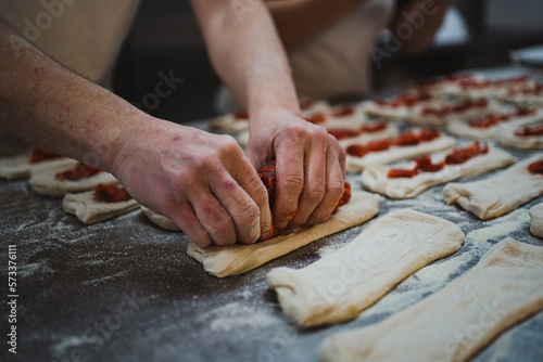 Baker man putting chorizo meat on bread dough to make stuffed bread sticks