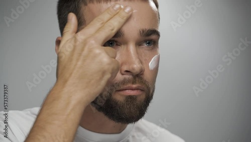 Man is applying moisturizing cream on his face