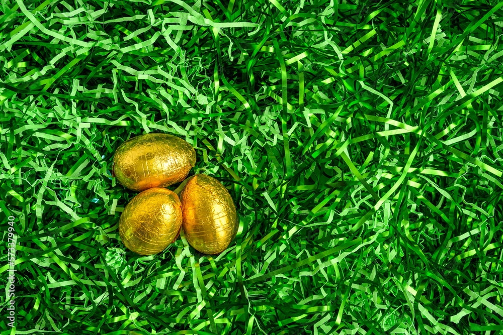 Three gold foil wrapped chocolate easter eggs in a nest of easter grass, as a holiday background
Three gold foil wrapped chocolate easter eggs in a nest of easter grass, as a holiday background