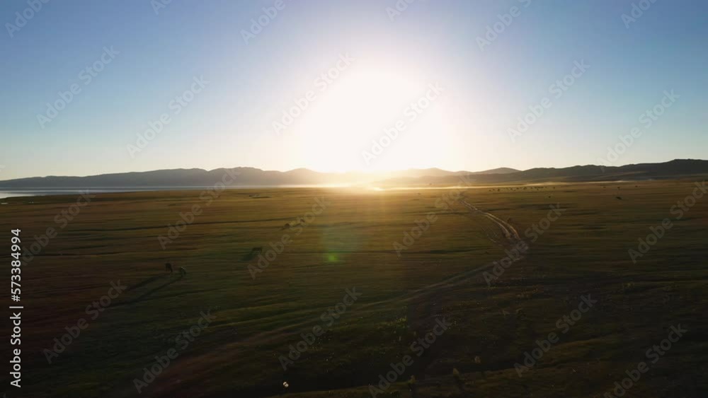 Epic cinematic drone shot of the sun lens flare over the horses down by the Song-Kol lake in Kyrgyzstan Epic cinematic drone shot of the sun lens flare over the horses down by the Song-Kol lake in Kyrgyzstan