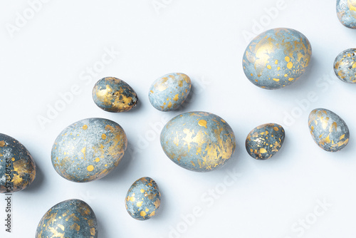 Blue Easter eggs with golden spots on light blue Easter background. Chic Easter greeting card  flat lay  Diagonal composition.