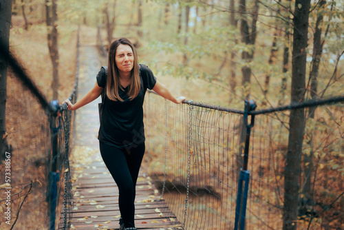 Anxious Woman Afraid of Heights Crossing a Bridge. Stressed travel girl suffering from acrophobia conquering her fears
