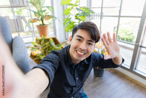 A handsome asian man relax and take selfie shot in living room in his house