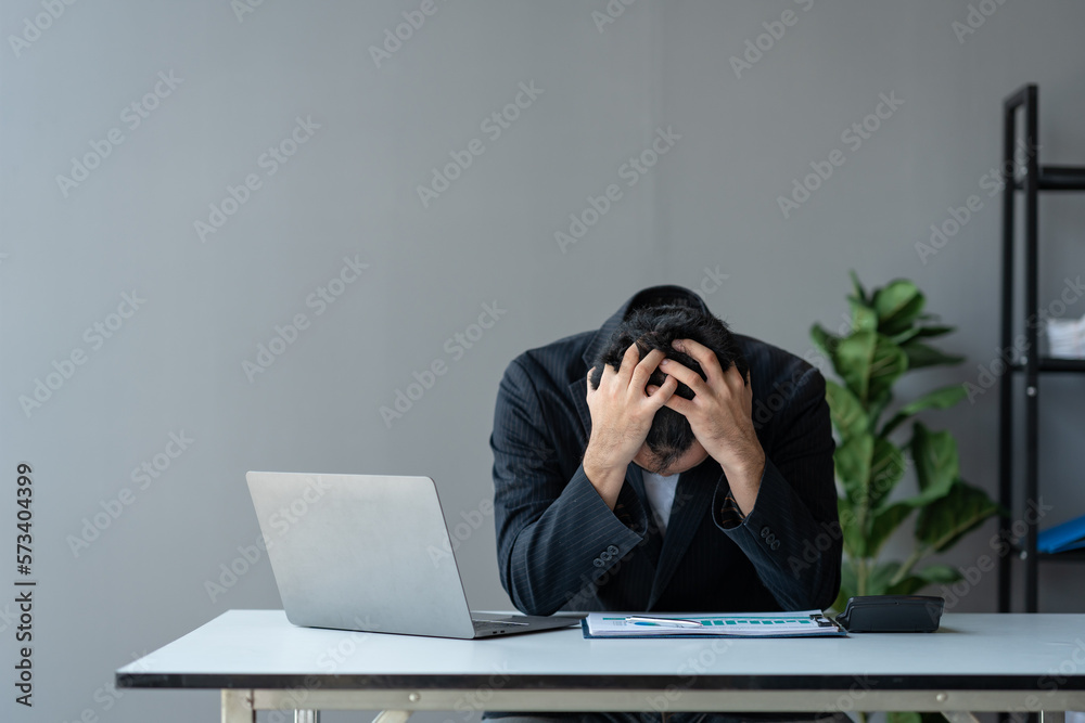 Young asian businessman suffering from stress, eyestrain, headache searching for financial information, stats, graphs, income charts. while working online on laptop computer at office. Young asian businessman suffering from stress, eyestrain, headache searching for financial information, stats, graphs, income charts. while working online on laptop computer at office.