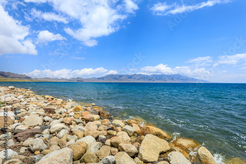 Beautiful Sayram Lake natural scenery in Xinjiang, China. Clear lake water and rocks under blue sky.