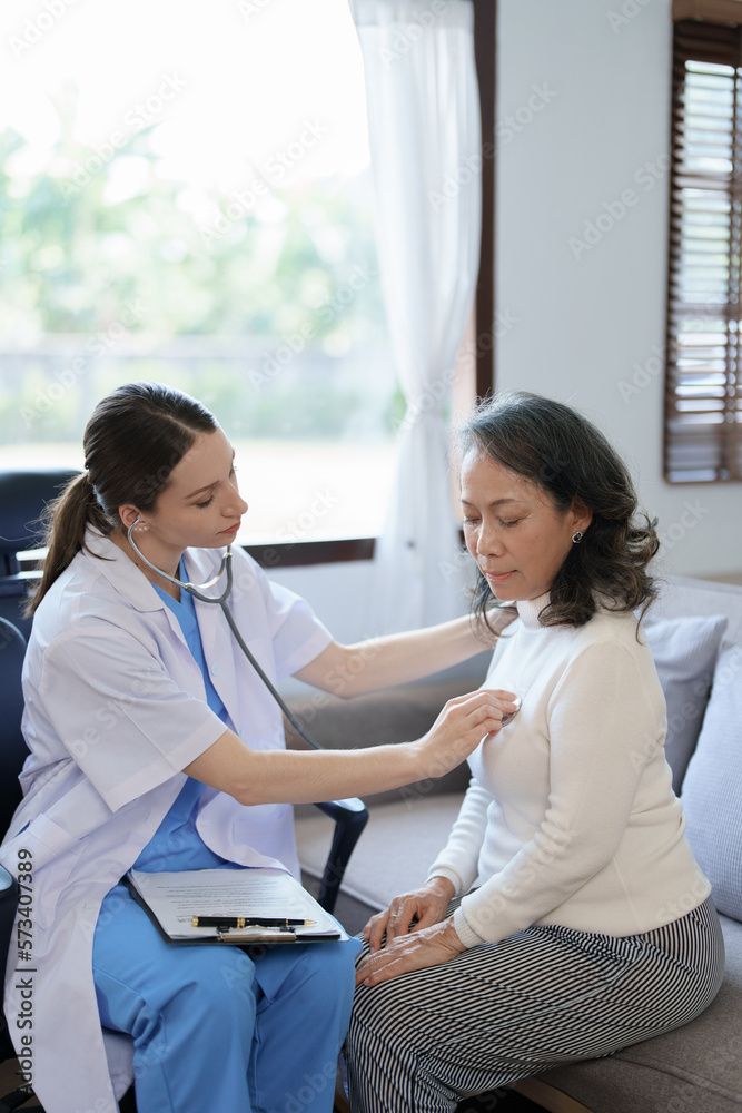 Obraz premium Portrait of a female doctor using a stethoscope to check the pulse of an elderly patient.