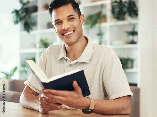 Portrait, man and reading book to relax, hobby and happiness in living room, peace and literature. Face, male and gentleman with novel, journal and knowledge in lounge, smile and cheerful in home