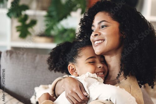 Black family, love and hug by girl and mother on a sofa, happy and relax in their home together. Mom, daughter and embrace on a couch, cheerful and content while sharing a sweet moment of bonding