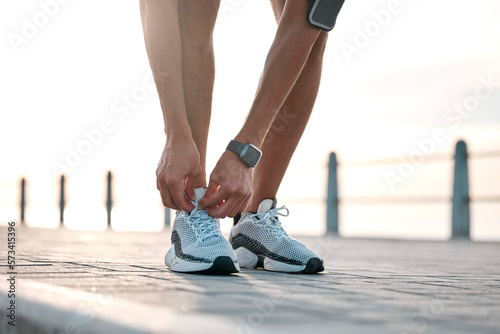 Fitness, running and man tie shoes by ocean ready for exercise, marathon training and cardio workout. Start sports mockup, athlete and feet of male runner with shoelace for wellness and health