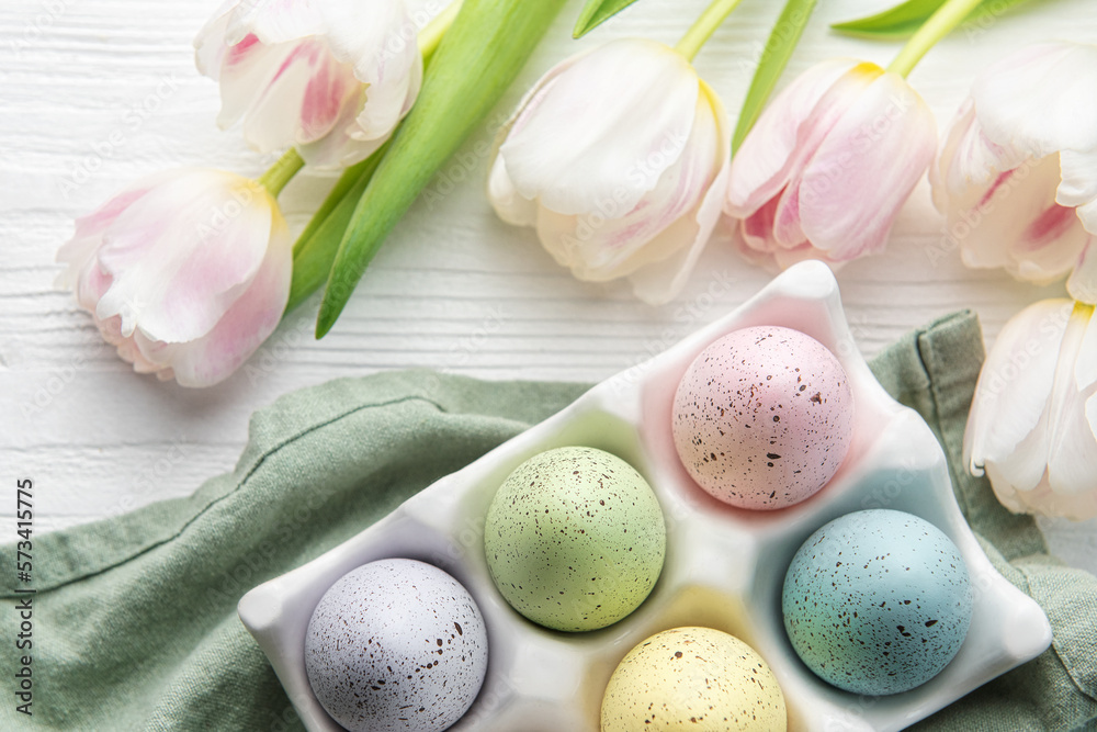 Holder with Easter eggs painted pastel colors on a white wooden background. Holder with Easter eggs painted pastel colors on a white wooden background.