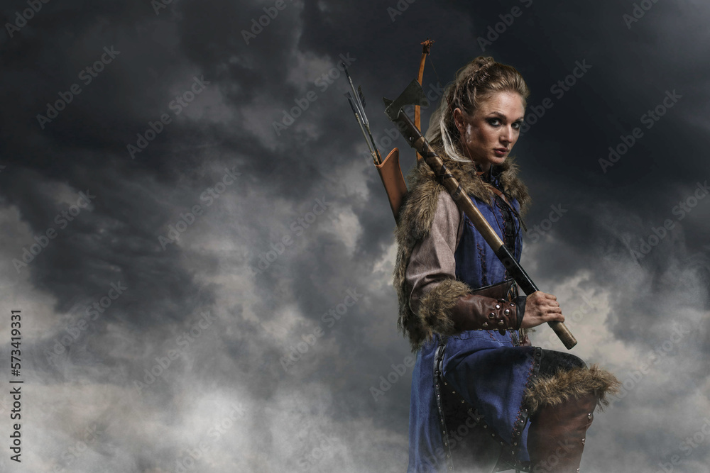 Beautiful female viking woman warrior in battle with ax and bow with arrows. Amazon fantasy blonde