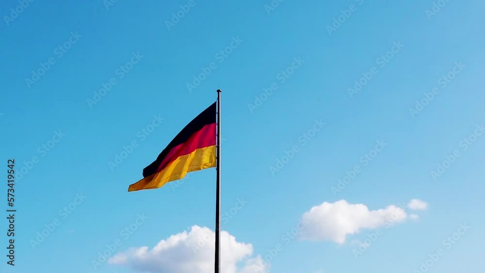 Zoomed in slow motion shot of waving German flag against light blue sky Zoomed in slow motion shot of waving German flag against light blue sky