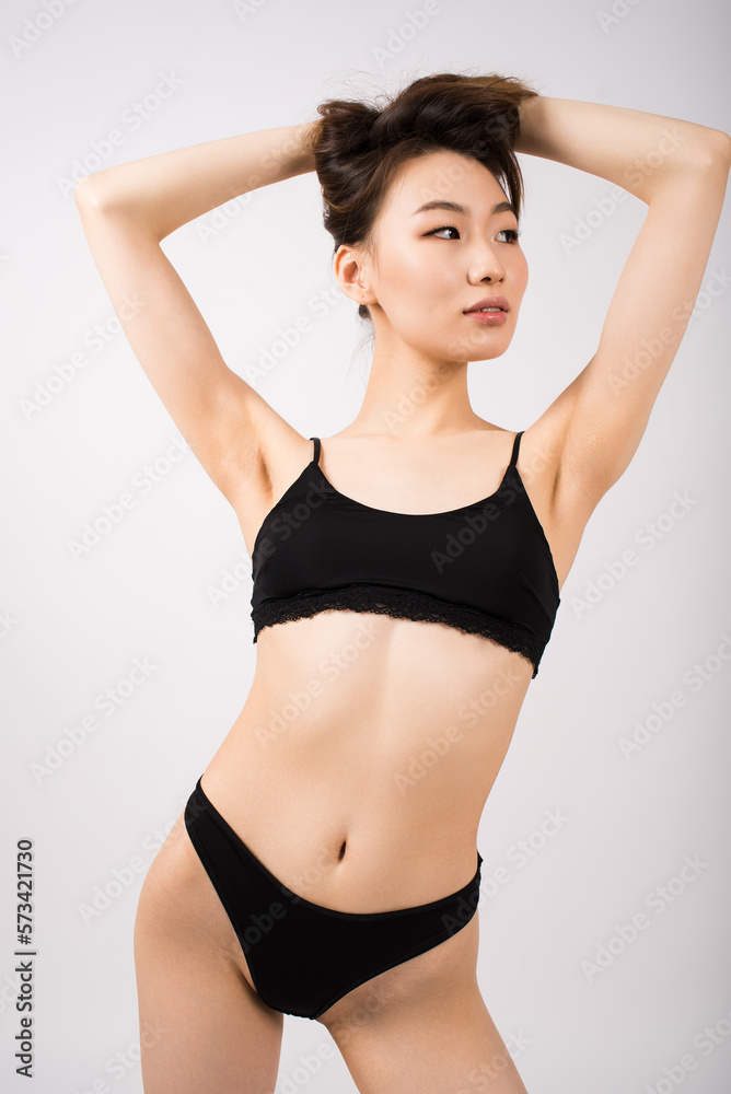 Fototapeta premium Young Asian girl in lingerie on a white background.