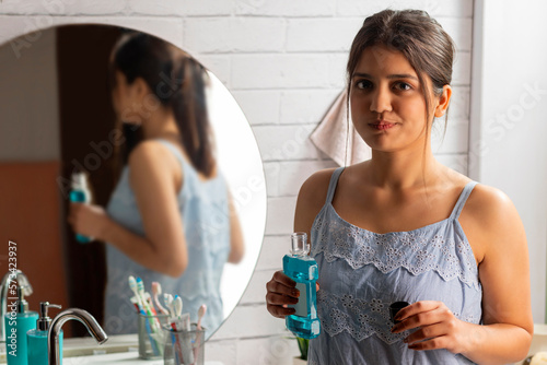 Woman rinsing mouth with mouthwash in bathroom