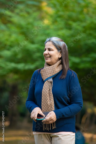 Indian woman in winter wear standing at park.