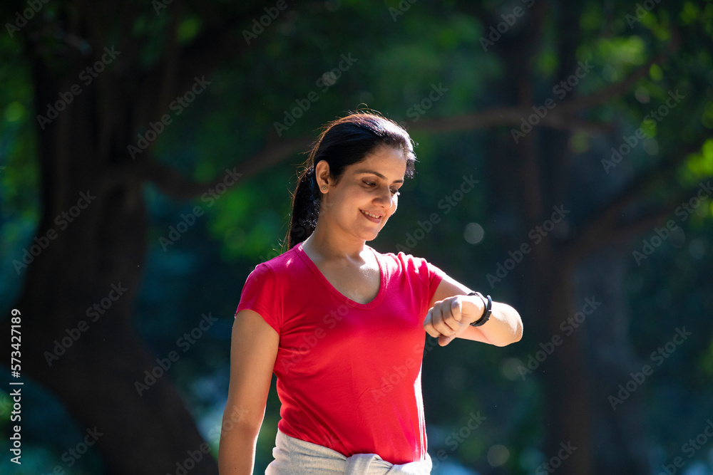 Indian young woman runner checking time in wristwatch after jogging. Indian young woman runner checking time in wristwatch after jogging.