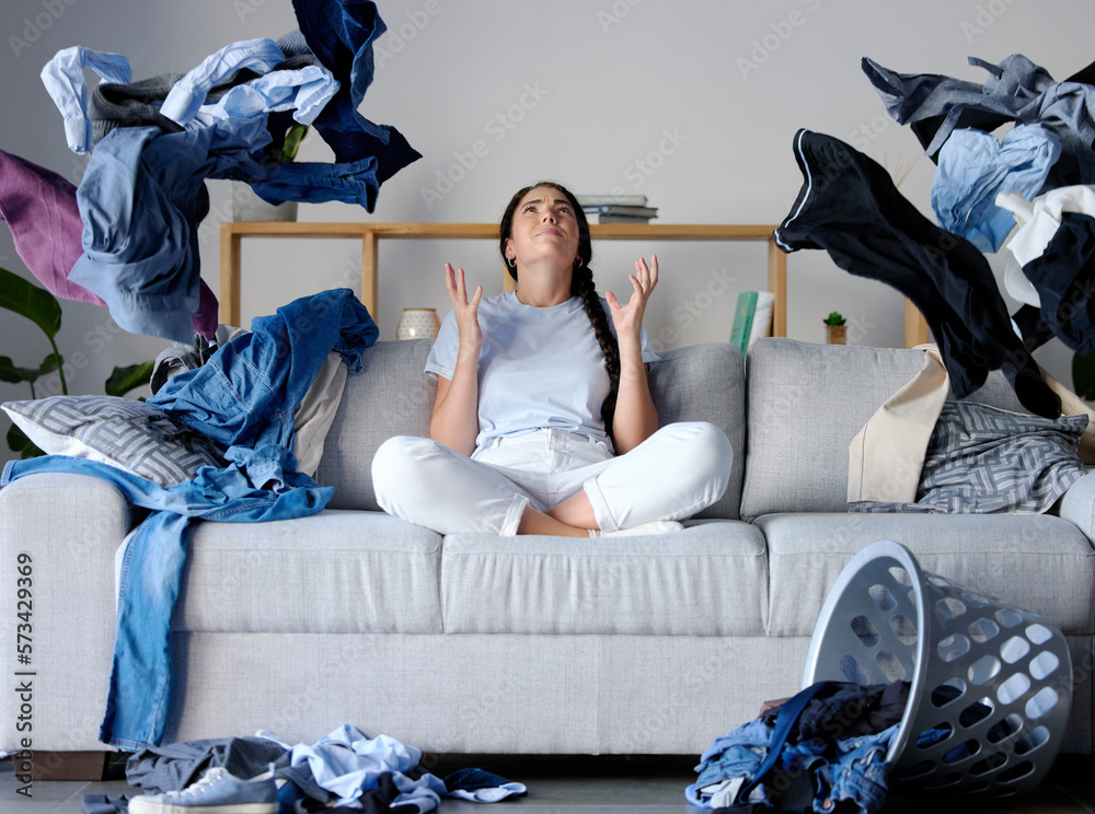Laundry, frustration and woman on sofa in messy living room with ...