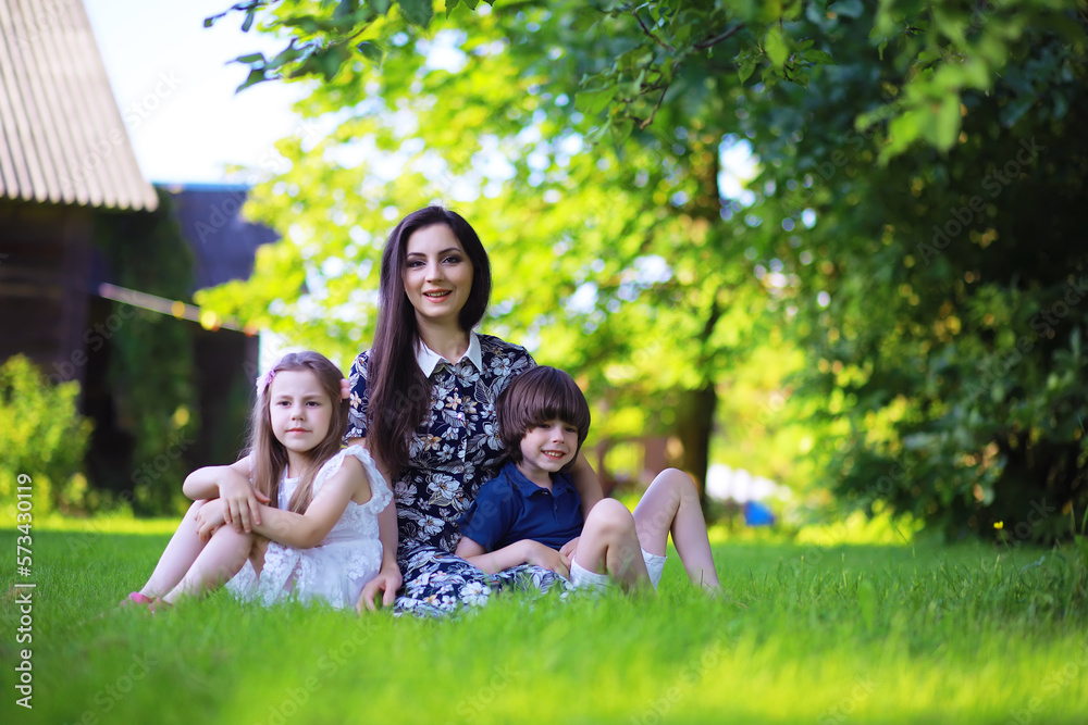Fototapeta premium Young large family on a summer morning walk. Beautiful mother with children is playing in the park.