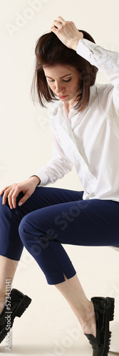 Woman in bad mood, bored and sad, sits on chair and puts hands on head