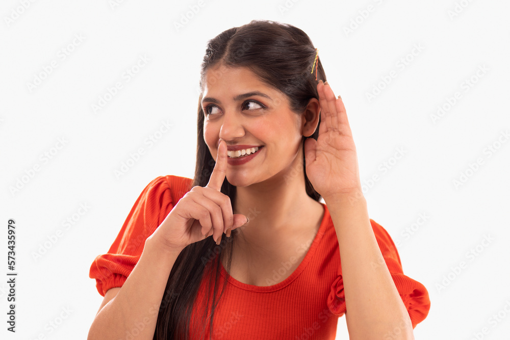 Portrait of beautiful woman showing hush gesture against white background Portrait of beautiful woman showing hush gesture against white background