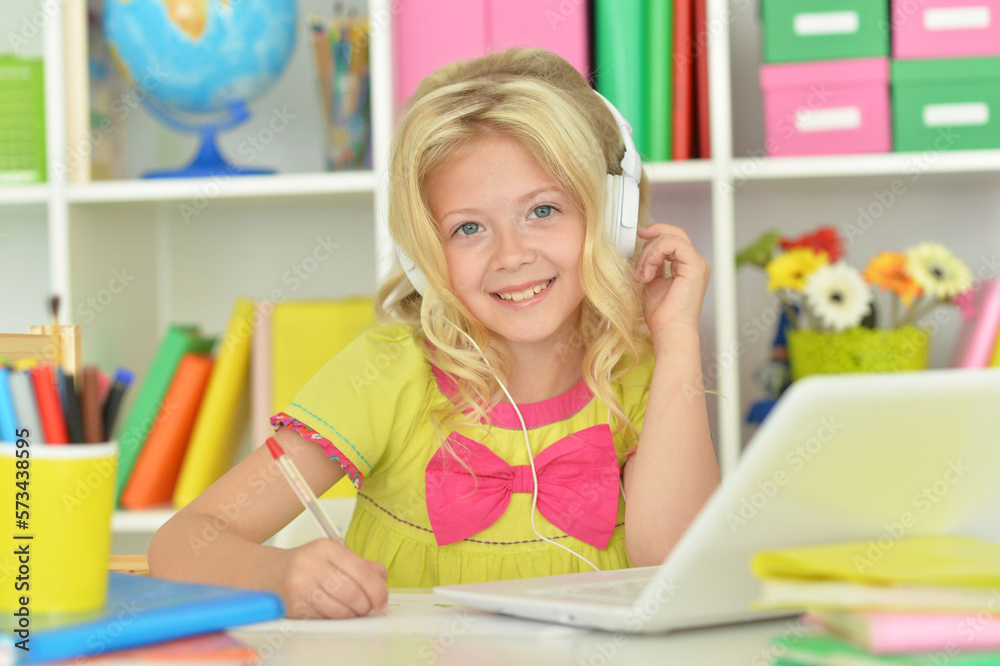 girl in headphones ding with laptop sitting at desk girl in headphones ding with laptop sitting at desk