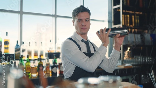 The profession bartender. Making a cocktail at bar in a restaurant. The bartender mixes the ingredients of an alcoholic cocktail by shaking a shaker