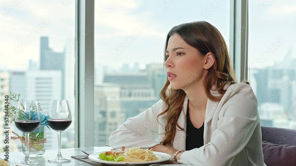 Face of beautiful woman is upset because her boyfriend arrives late for dinner at a restaurant Face of beautiful woman is upset because her boyfriend arrives late for dinner at a restaurant