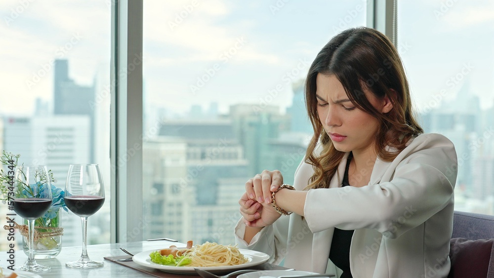 Beautiful woman looking at the watchat and upset because her boyfriend arrives late for dinner at a restaurant Beautiful woman looking at the watchat and upset because her boyfriend arrives late for dinner at a restaurant
