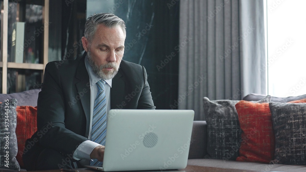 Male senior executive wearing suit and using laptop to work in the office Male senior executive wearing suit and using laptop to work in the office