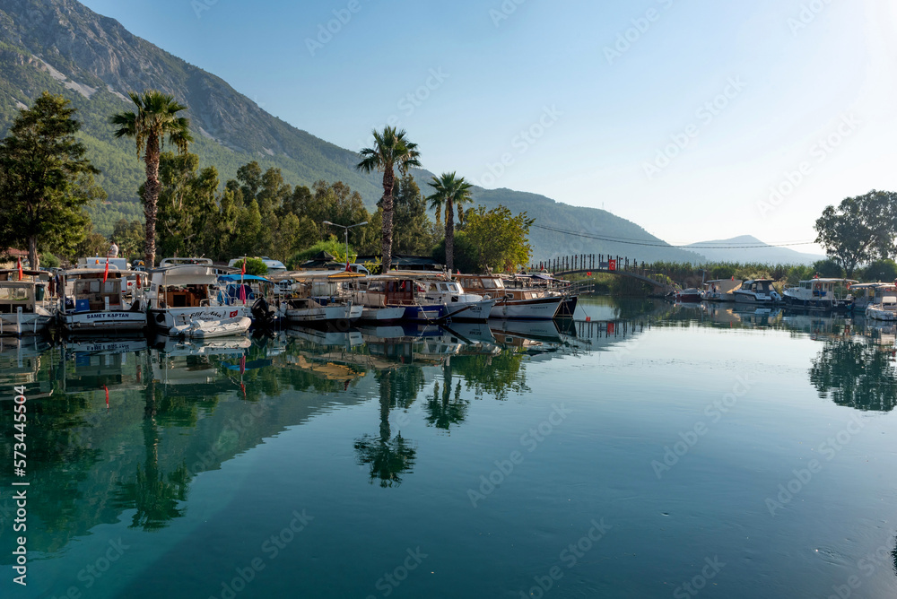 Obraz premium Boats moored in the beautiful harbour at the entrance to the Azmak River, at the Turkish Riviera seaside town of Akyaka on the south west coast of Turkey
