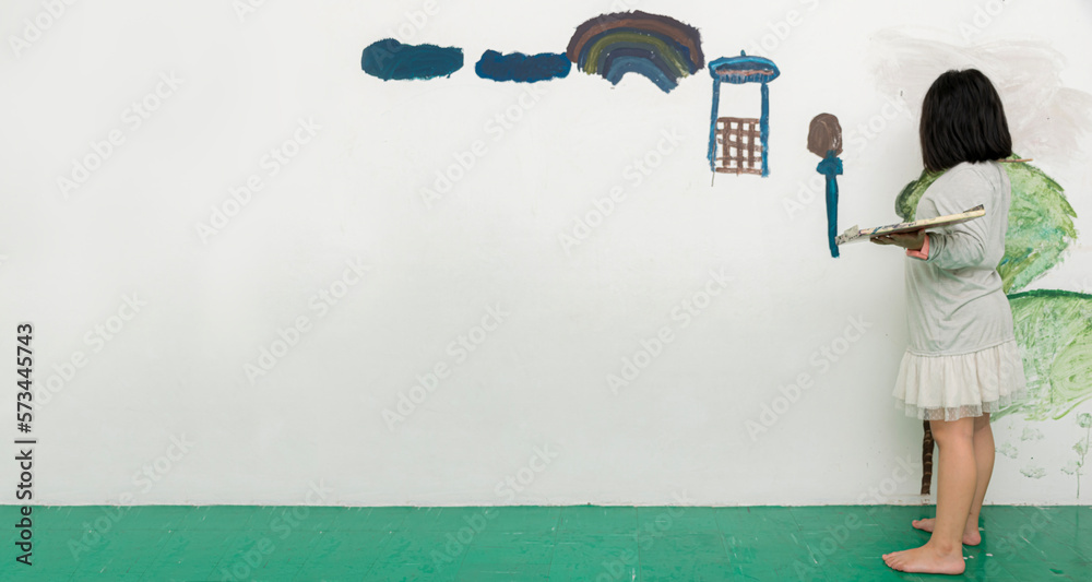 paint brush painting wall, back view. Painting of a cute little girl on