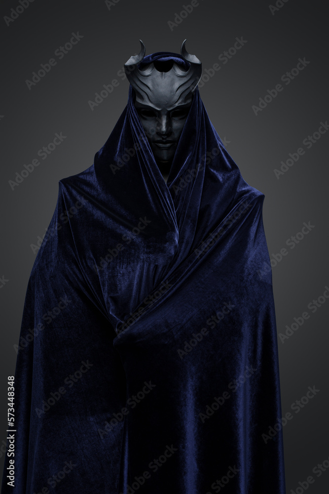 Studio shot of dark cultist dressed in black mask and dark cloak.