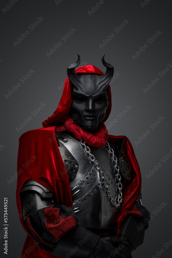 Portrait of dark member of mysterious cult dressed in red robe and black mask. Portrait of dark member of mysterious cult dressed in red robe and black mask.