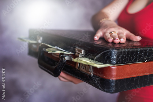 closeup woman in red dress holding briefcase full of dollars