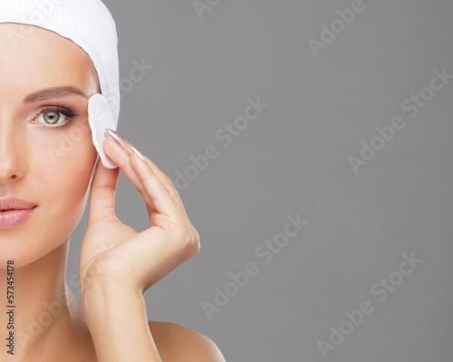 Young woman cleaning her face with a cotton pads. Girl removing cosmetics with hygienic discs.