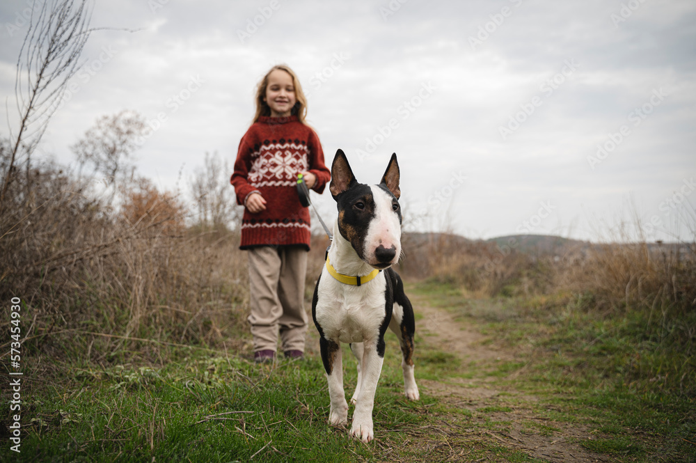 Girl standing with Bull Terrier dog amidst grass