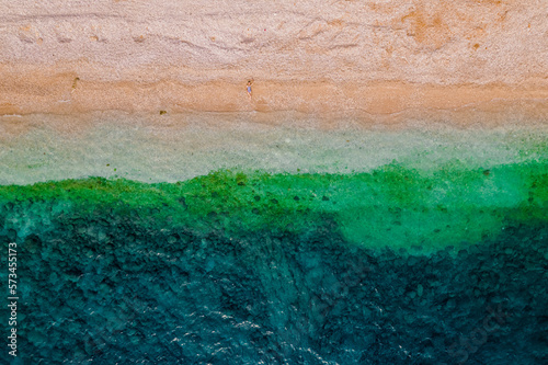 Bird's-eye view of a lying girl who is sunbathing on the beach. Drone shot top view.