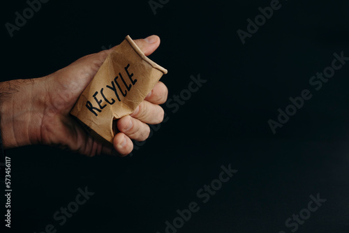 Hand of man crushing reusable cup against black background