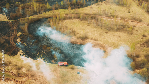 Aerial View Spring Dry Grass Burns During Drought Hot Weather. Bush Fire And Smoke. Fire Engine, Fire Truck On Firefighting Operation. Wild Open Fire Destroys Grass. Ecological Problem Air Pollution.