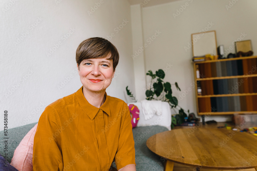 Smiling woman sitting on sofa at home