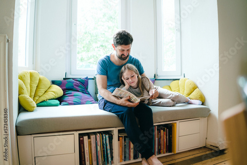 Father telling story to daughter at home photo