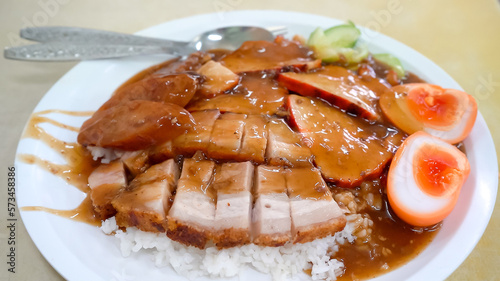a plate of roasted red pork, crispy pork, and a perfectly half-boiled egg served atop a bed of steaming white rice, combined with the crunch of the crispy pork and the rich yolk