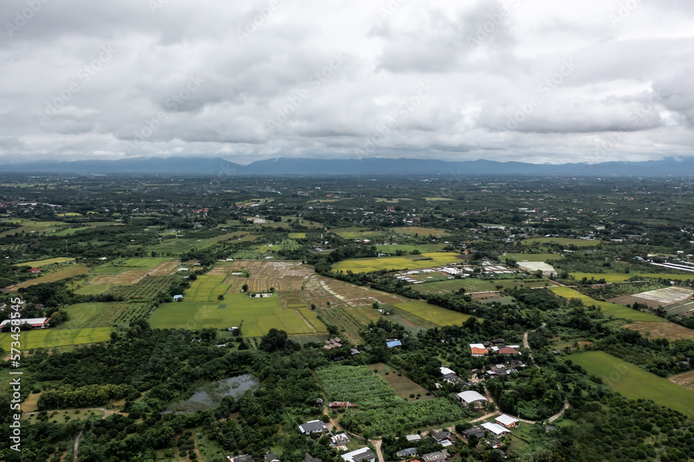 seen from a high perspective. Note the contrast between the sky's circling clouds and the green grass trees at Pa Sang District, Lamphun Province, Thailand.