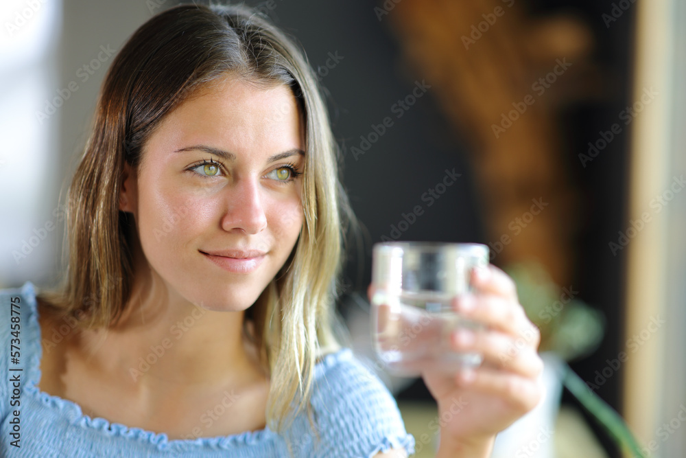Happy teen holding water glass looking away Happy teen holding water glass looking away