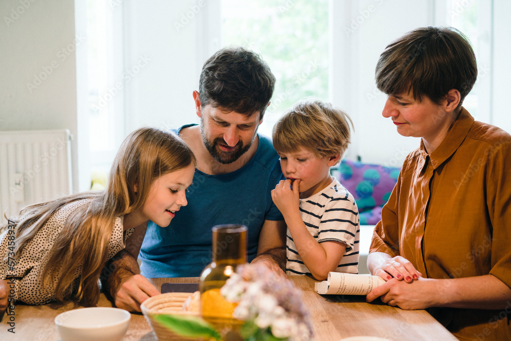 Family watching tablet PC together at dining table in home Family watching tablet PC together at dining table in home
