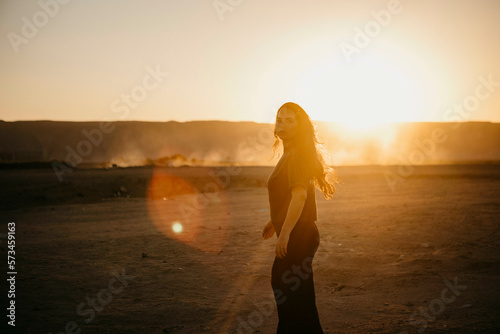 Woman walking on dirt road at sunset