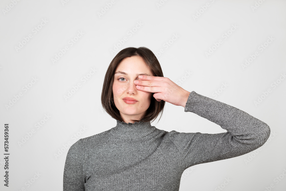 Young woman covering eye against white background Young woman covering eye against white background