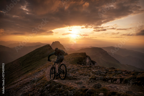 Man riding mountain bike on trail at sunset